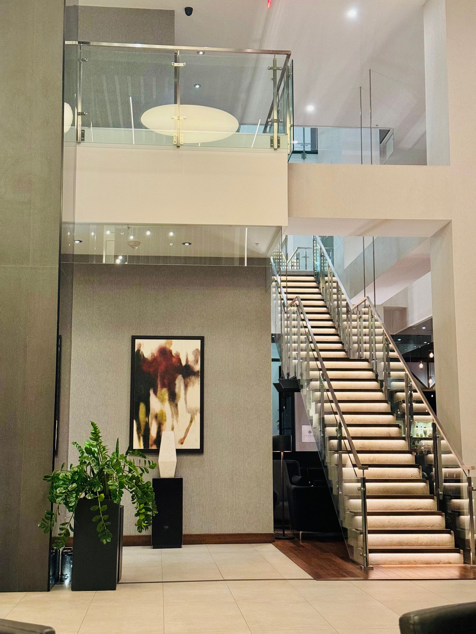 Interior staircase guarded by frameless glass panels with a slim metal handrail