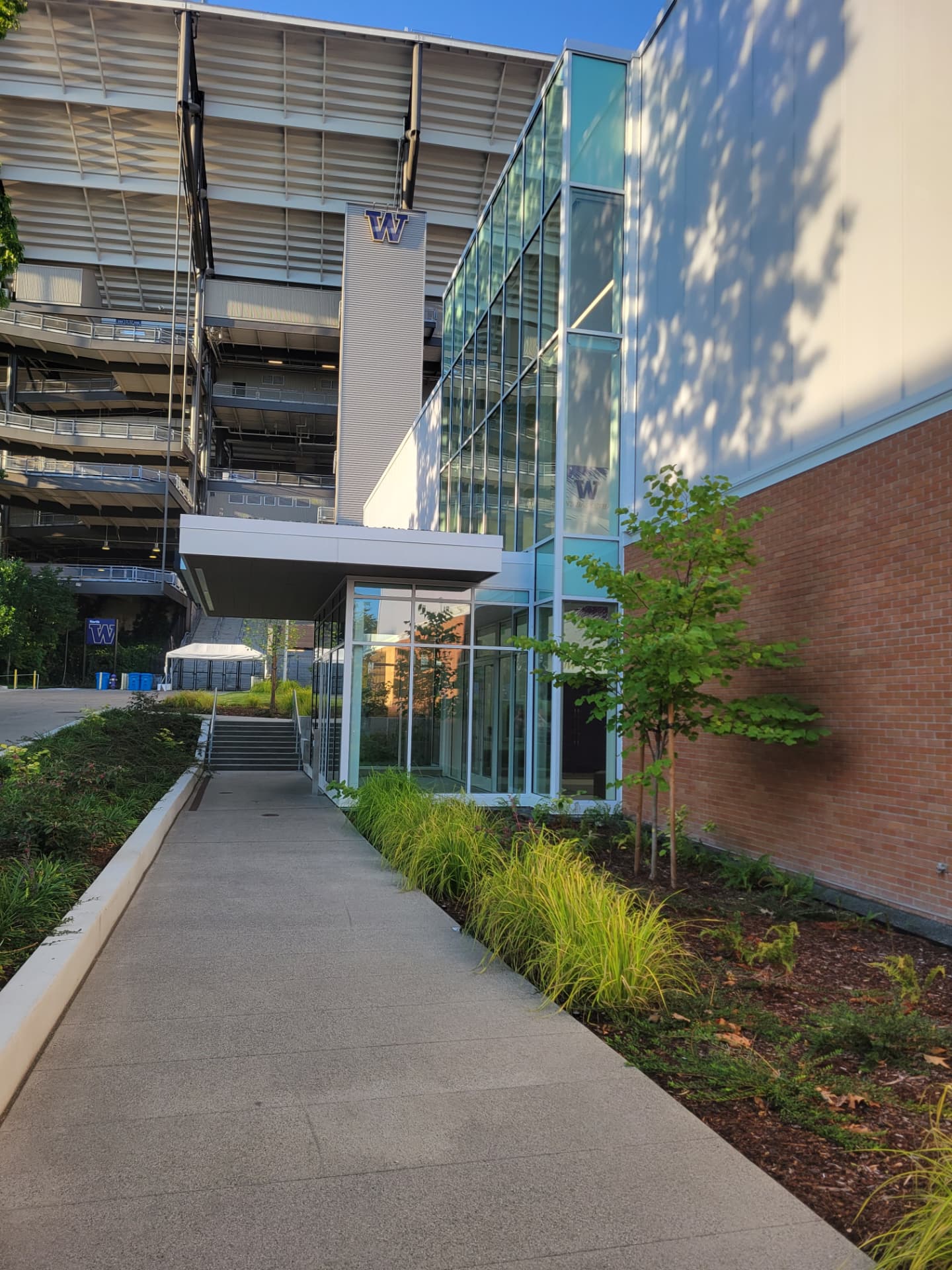 Glass lobby entrance and curtain wall beside a brick stadium building