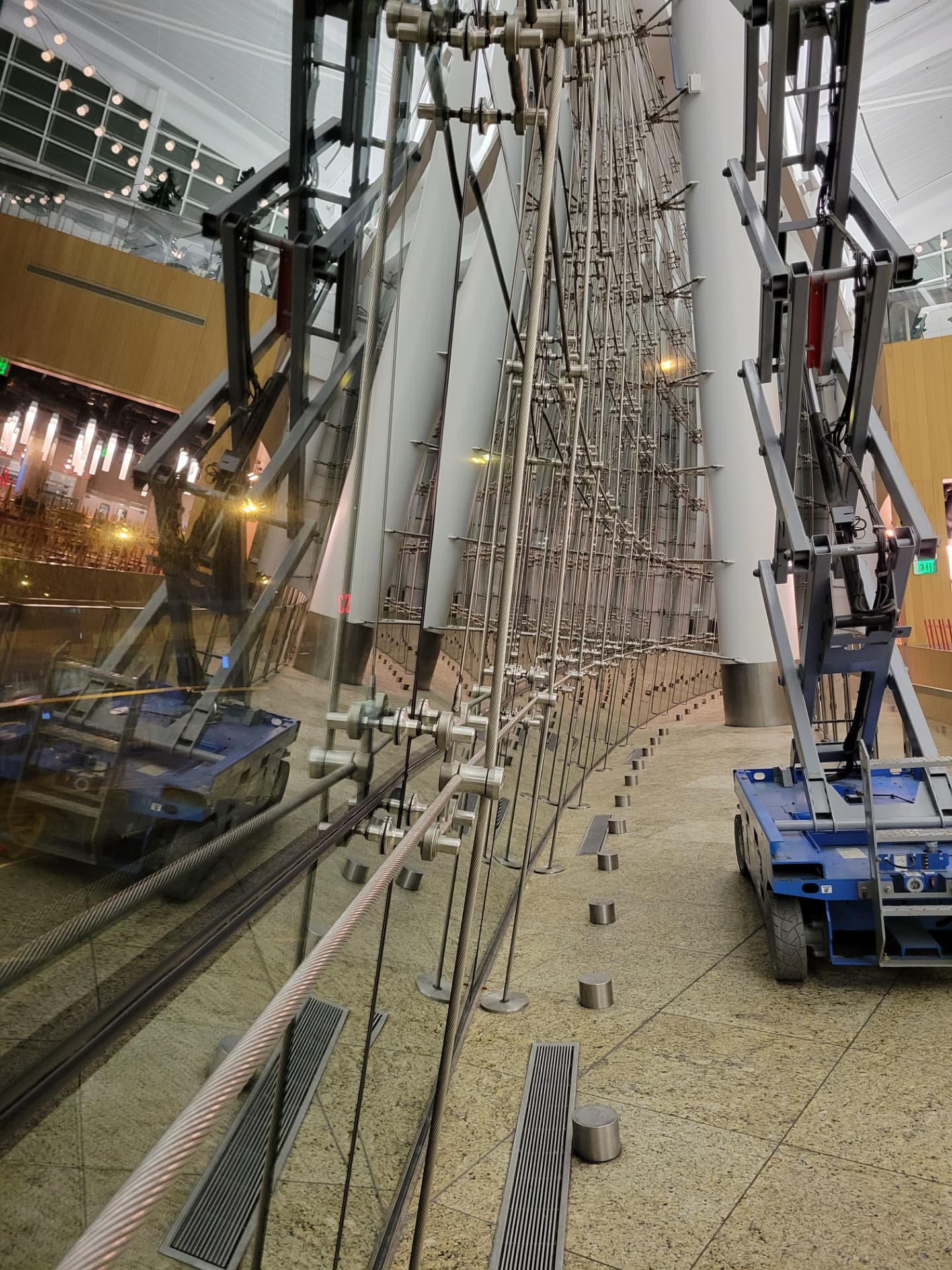 Tall glass wall held by vertical tension cables and stainless-steel fittings