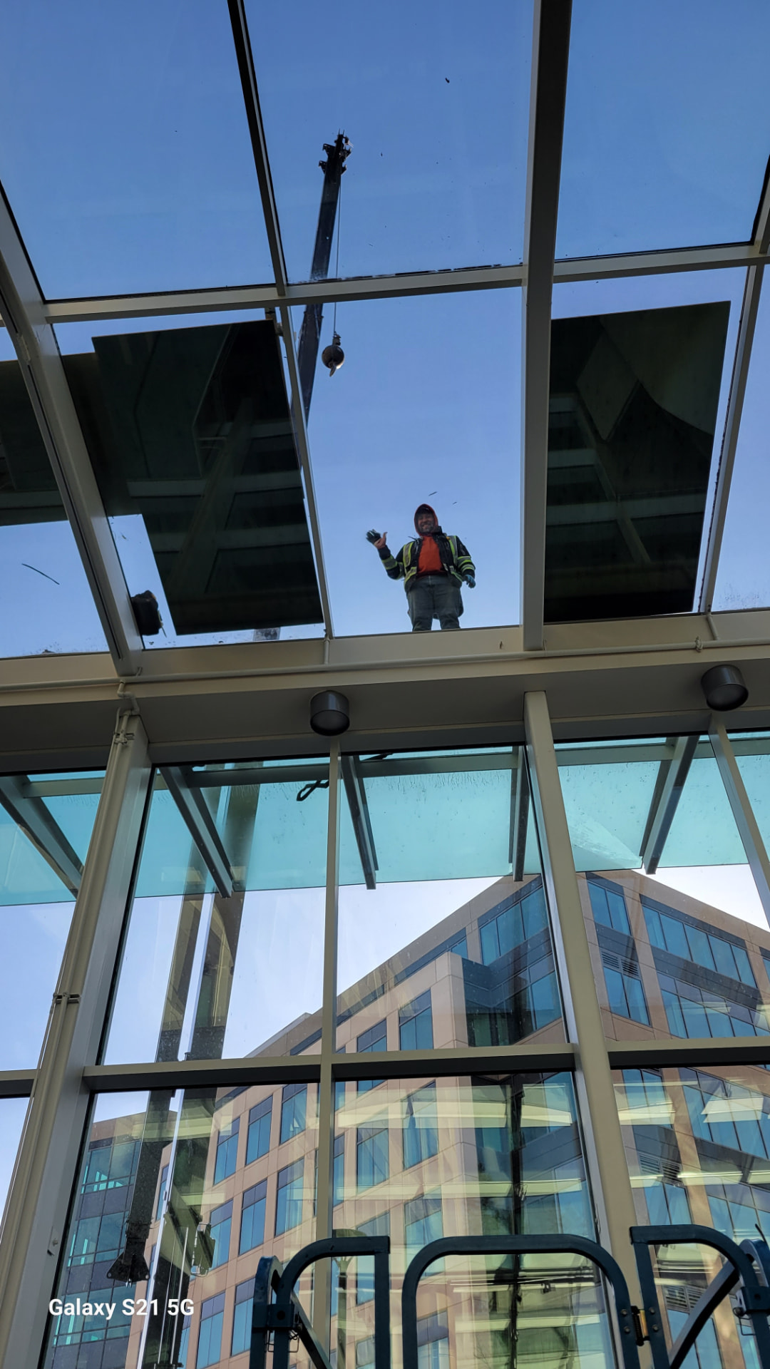 Glazier setting overhead glass panels into a steel-framed skylight canopy